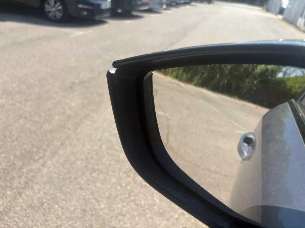Rétroviseur côté droit d'une Peugeot 308 PHEV 180 e-EAT8 Allure gris clair 2024, avec poignée de porte visible.