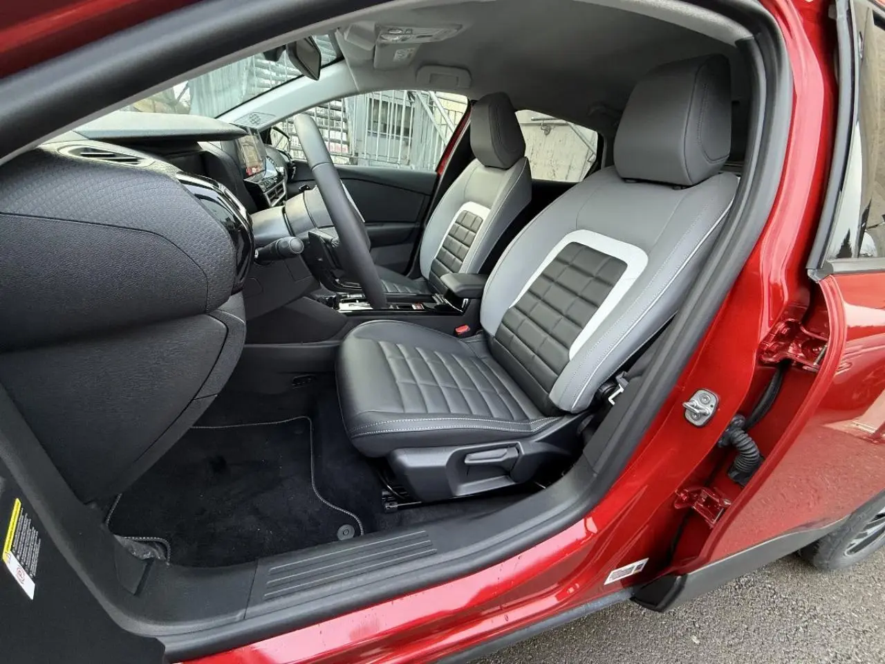 Intérieur du Citroën C4 2025 rouge elixir, vue côté conducteur ouverte, sièges bicolores gris et noir avec surpiqûres.