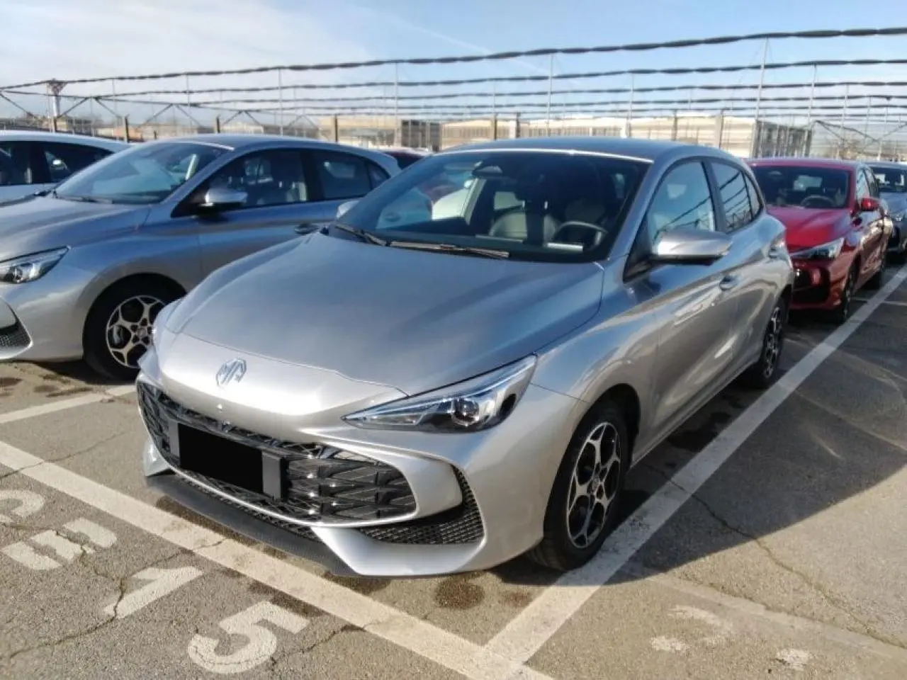 MG3 1.5 Hybrid+ 195 Luxury argent Cosmic en 3/4 avant droit, avec calandre large et jantes alliage 16 pouces.