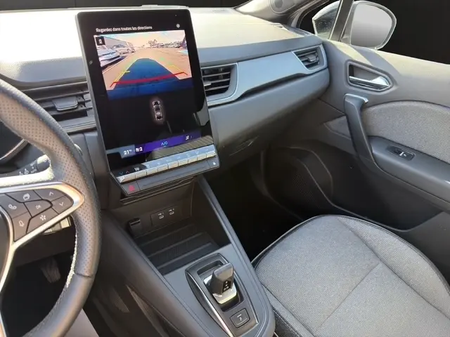 Vue intérieure côté passager du Renault Symbioz gris clair, avec écran tactile central vertical et volant multifonctions partiel visible.