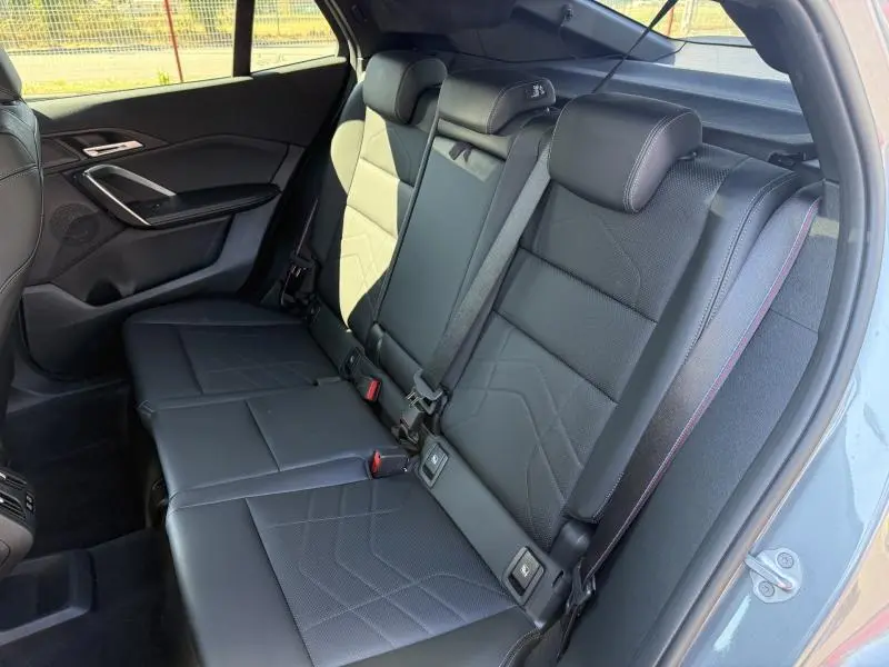 Vue intérieure côté droit des sièges arrière en cuir noir avec surpiqûres bleues du BMW X2 sDrive20dA 2025 Skyscraper Grey.