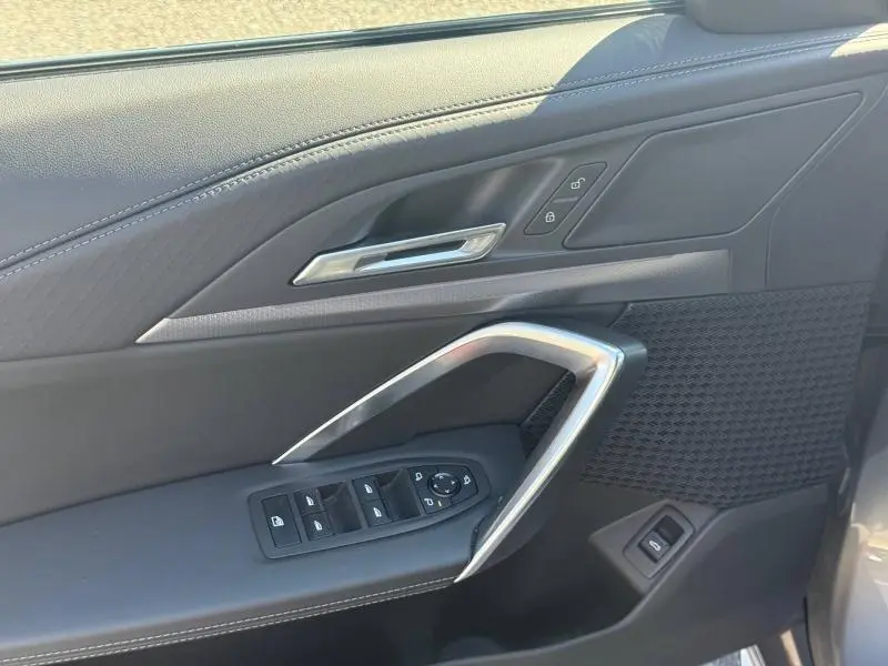 Détail de la porte côté conducteur du BMW X2 2025 Skyscraper Grey, avec commandes électriques et insert métal.