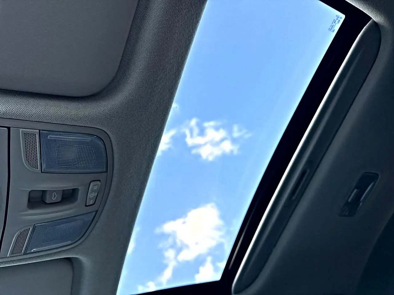 Toit ouvrant panoramique ouvert avec ciel bleu visible, intérieur gris foncé du Kia Stonic 2025 GT Line.