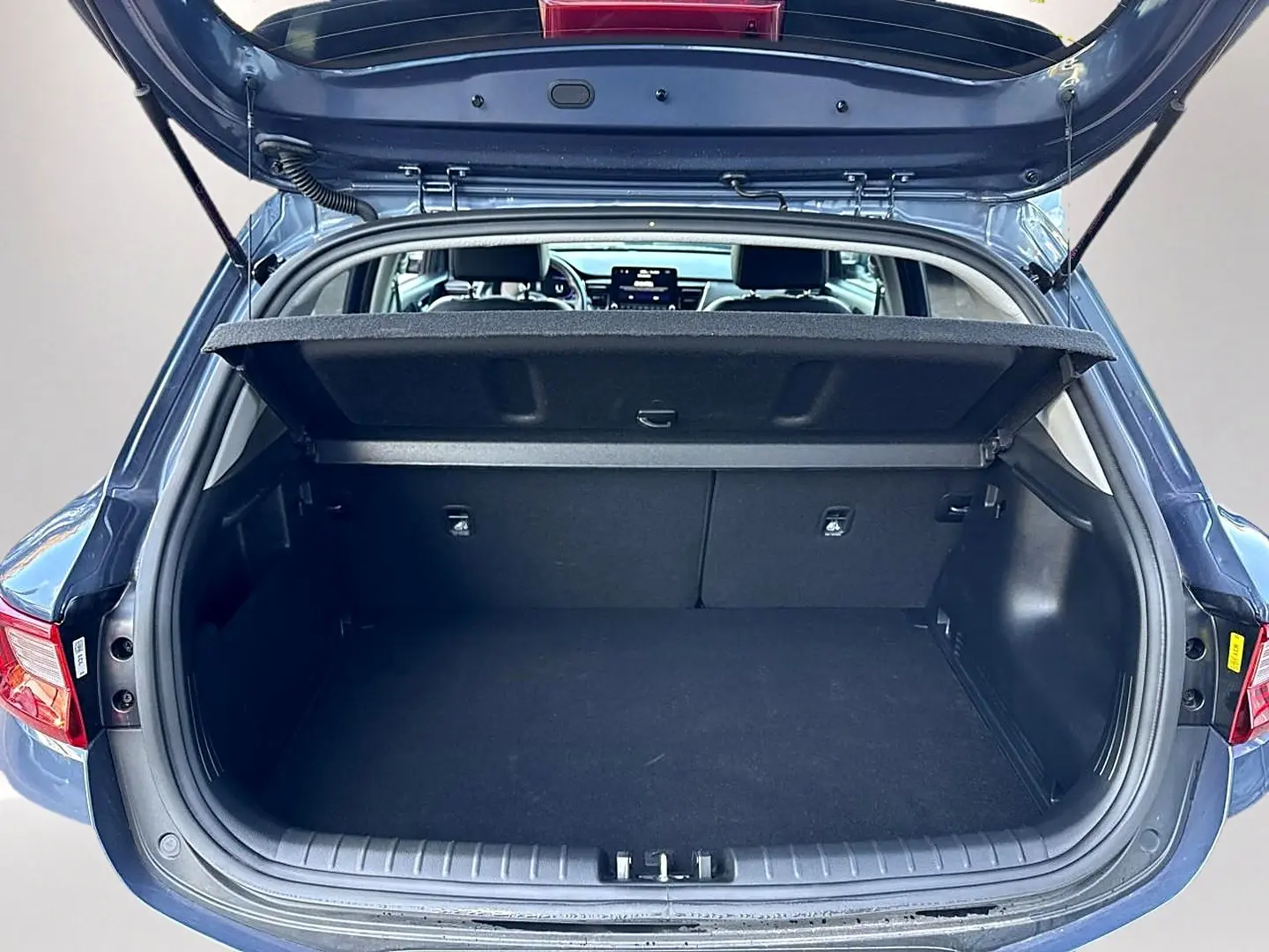 Coffre ouvert en vue arrière d'un KIA STONIC gris 2025, montrant l'espace de chargement et l'intérieur du véhicule.