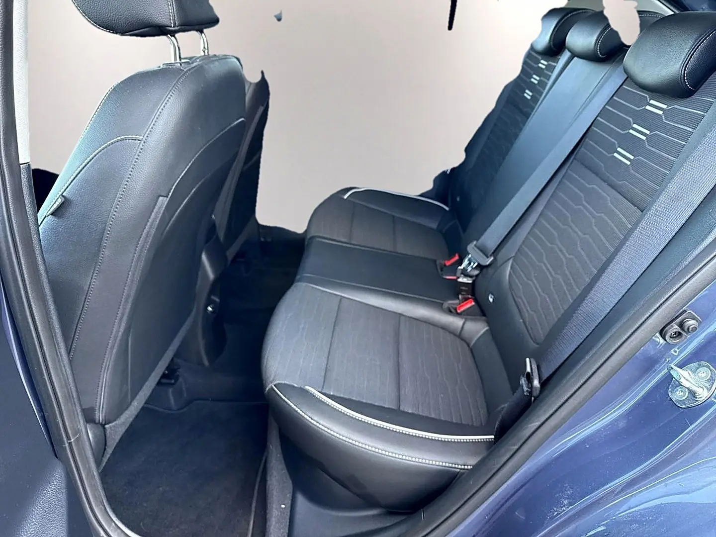 Vue côté droit des sièges arrière noirs en tissu et cuir du Kia Stonic 2025 avec ceinture de sécurité et porte ouverte.
