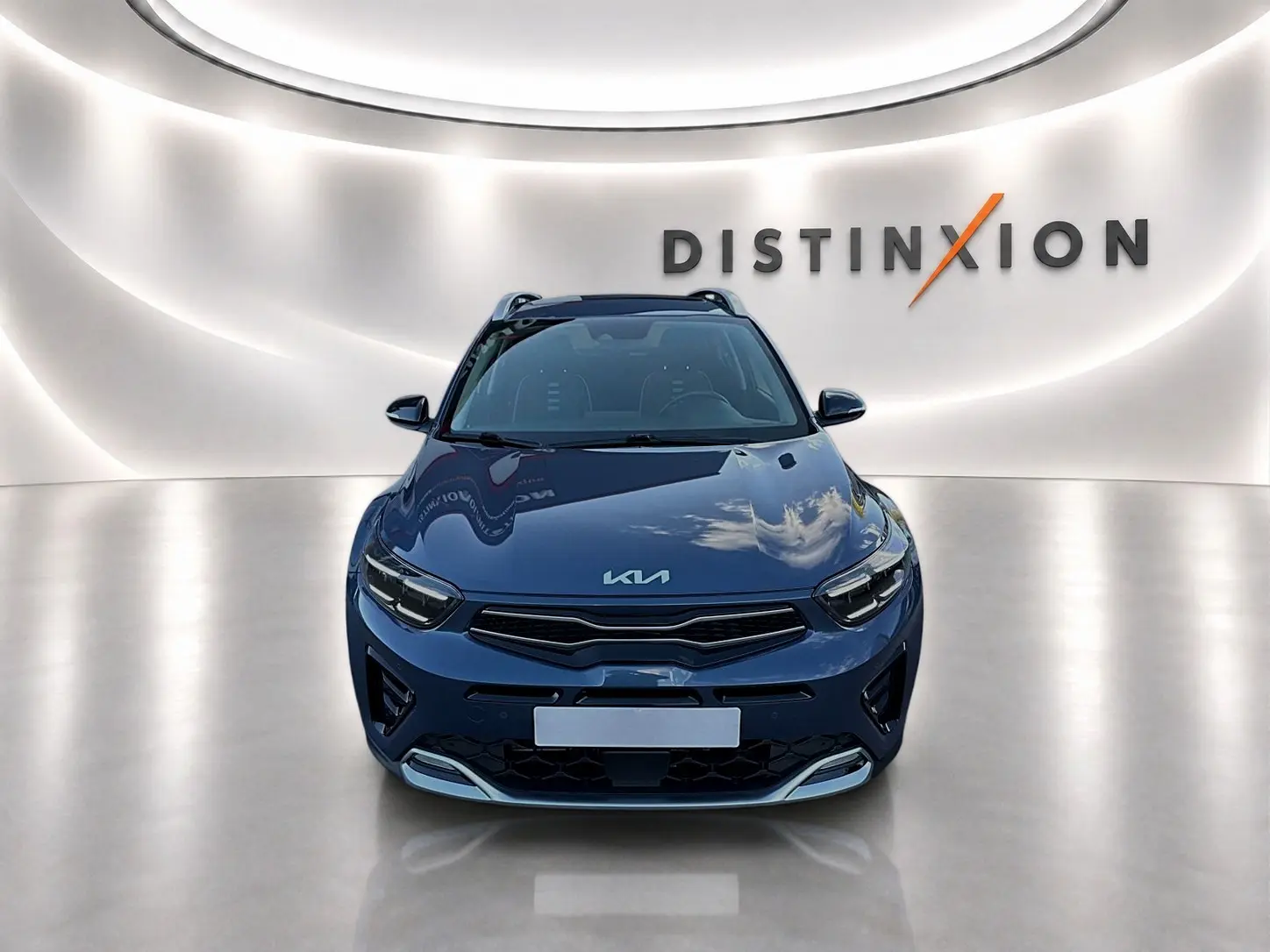 Vue avant d'un KIA Stonic gris métallisé avec calandre noire et logo KIA sur capot, dans un studio lumineux.