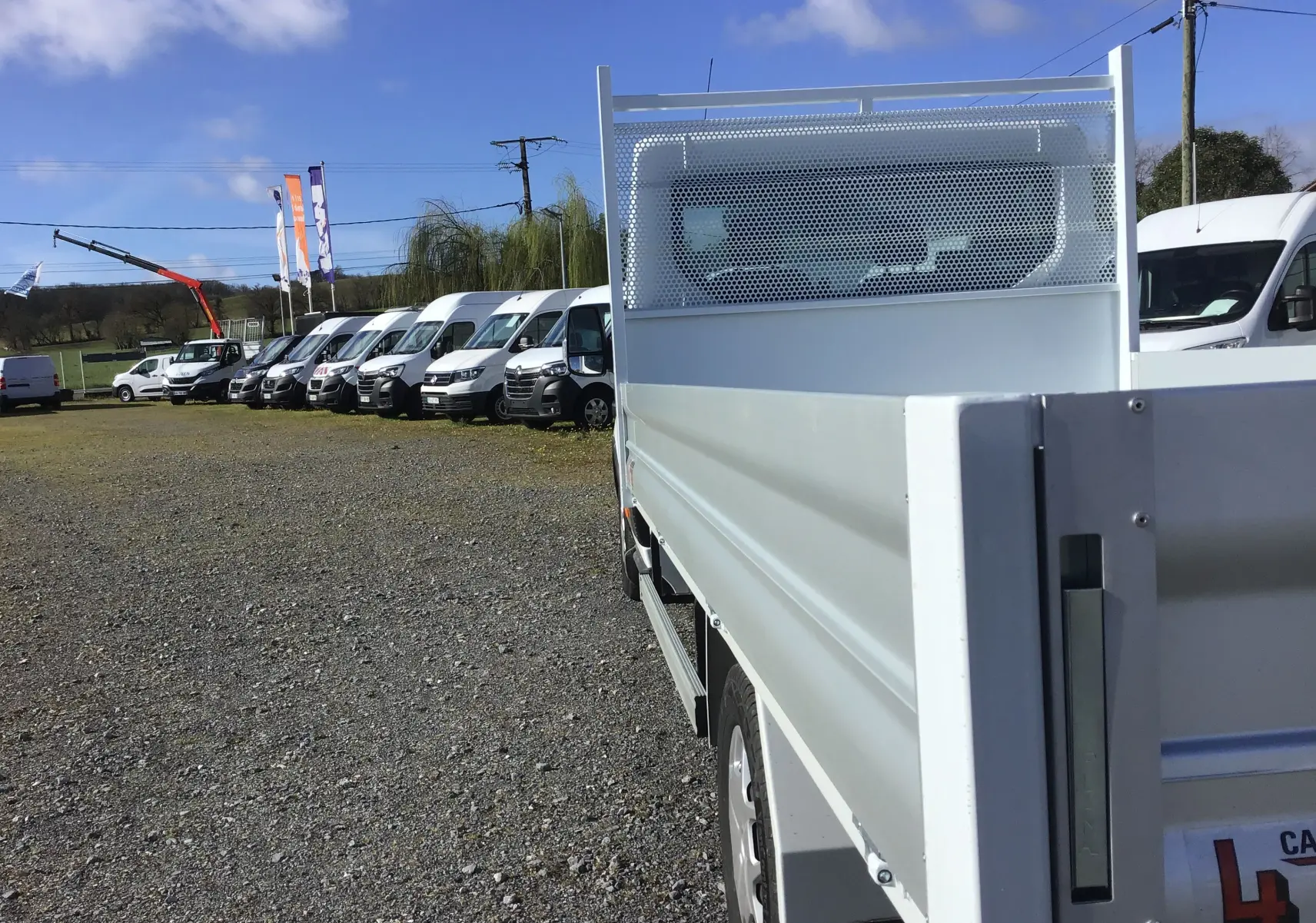 Vue arrière droite d'un Ford Transit Chassis Cabine blanc avec plateau 4 mètres et ridelles en aluminium.