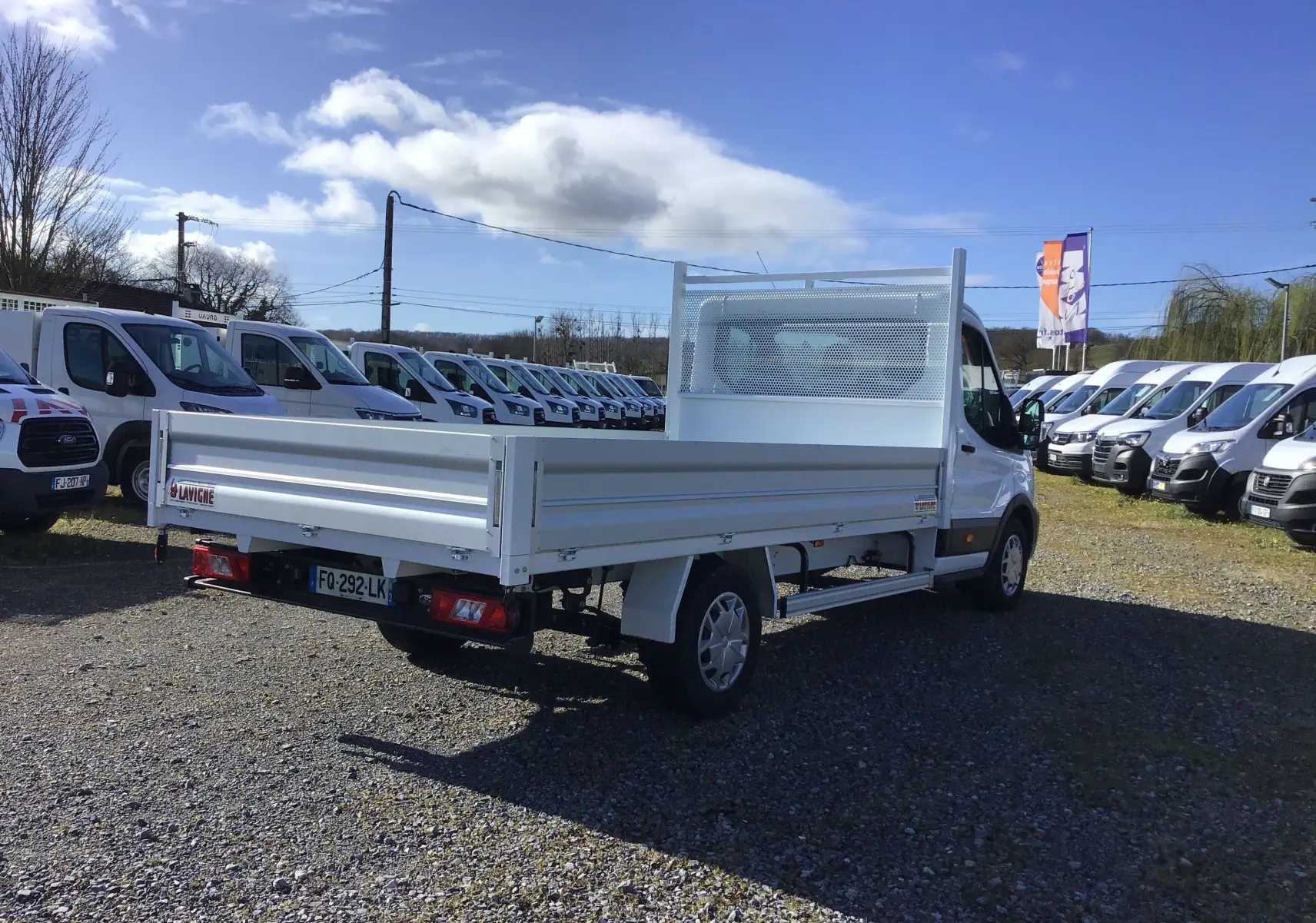 Ford Transit Chassis Cabine blanc vu en 3/4 arrière droit, avec plateau 4 mètres et ridelles en aluminium.
