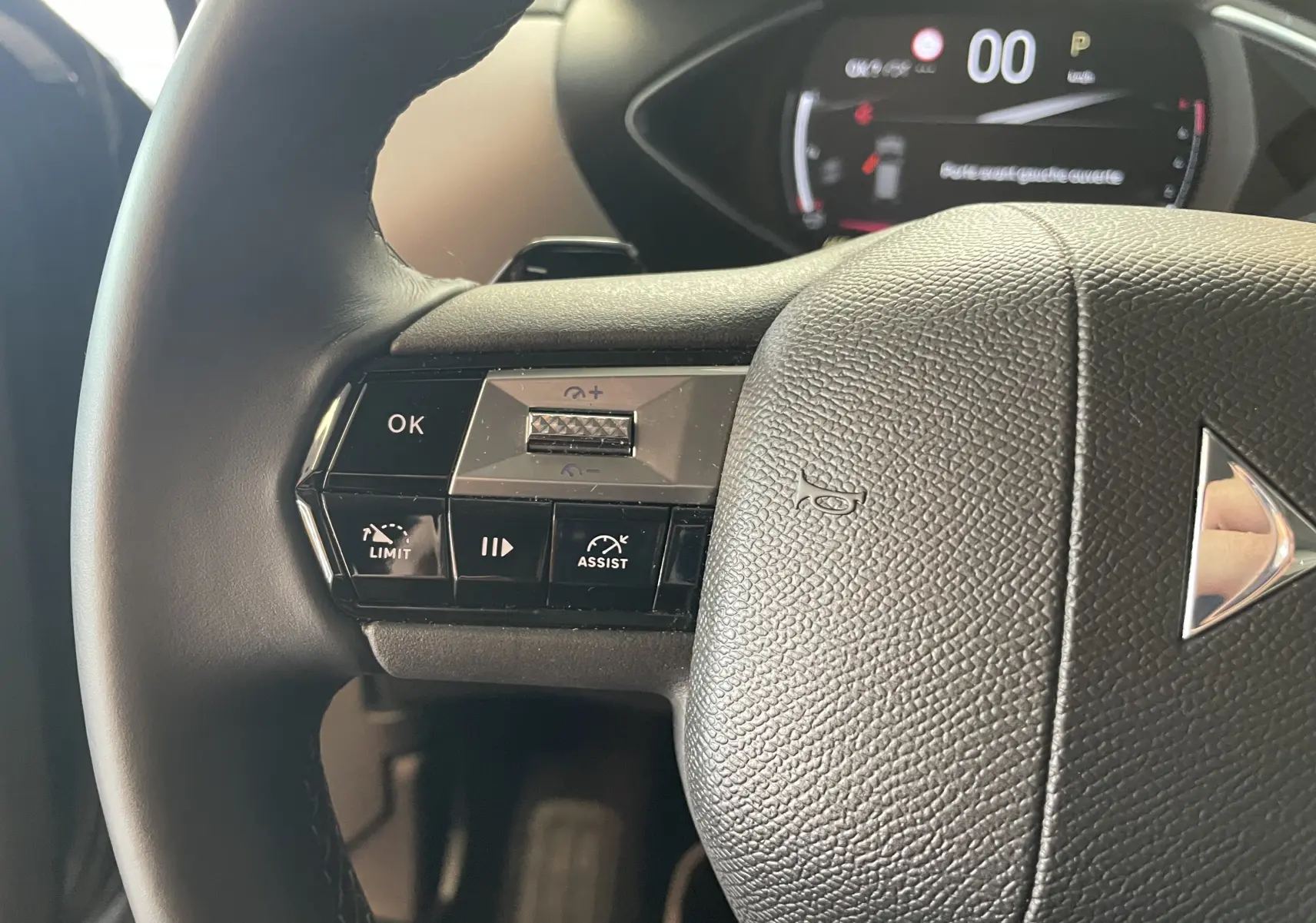 Gros plan sur le volant noir du DS3 Crossback 2024 avec commandes intégrées et logo DS au centre.