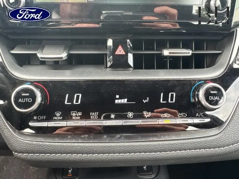 Vue rapprochée de la console centrale noire avec commandes climatisation bi-zone et affichage digital sur Toyota Corolla gris Manhattan.