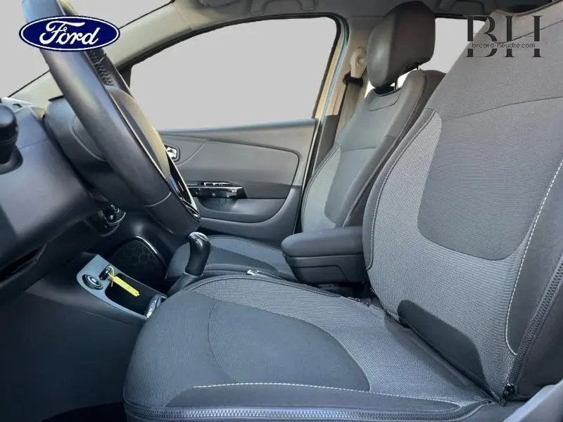 Vue intérieure côté conducteur montrant les sièges avant gris et la console centrale d'une Renault Captur 2015.
