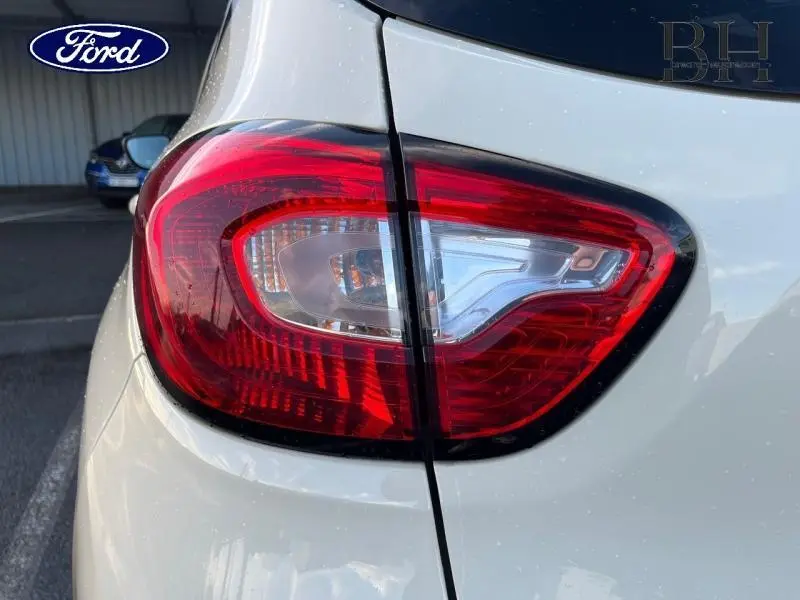 Gros plan sur le feu arrière droit rouge et blanc d'un Renault Captur beige cendré, toit noir étoilé.