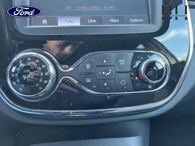 Panneau de commande de climatisation avec écran tactile et réglages circulaires dans un Renault Captur beige et noir.