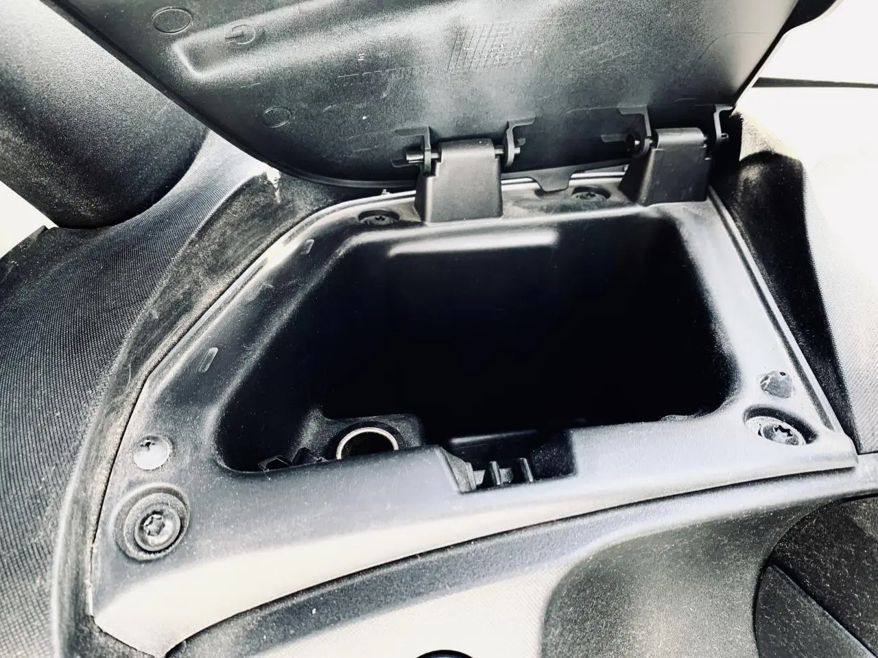Gros plan sur la boîte à gants ouverte côté droit de la Renault Twizy blanche, montrant l'intérieur vide et la texture noire.