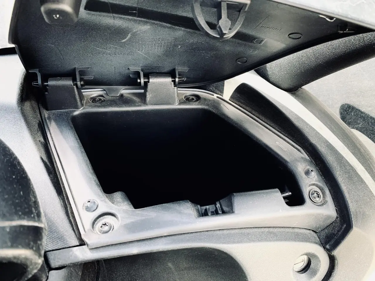 Gros plan sur la boîte à gants droite ouverte du Renault Twizy blanc, montrant l'intérieur vide et la charnière.