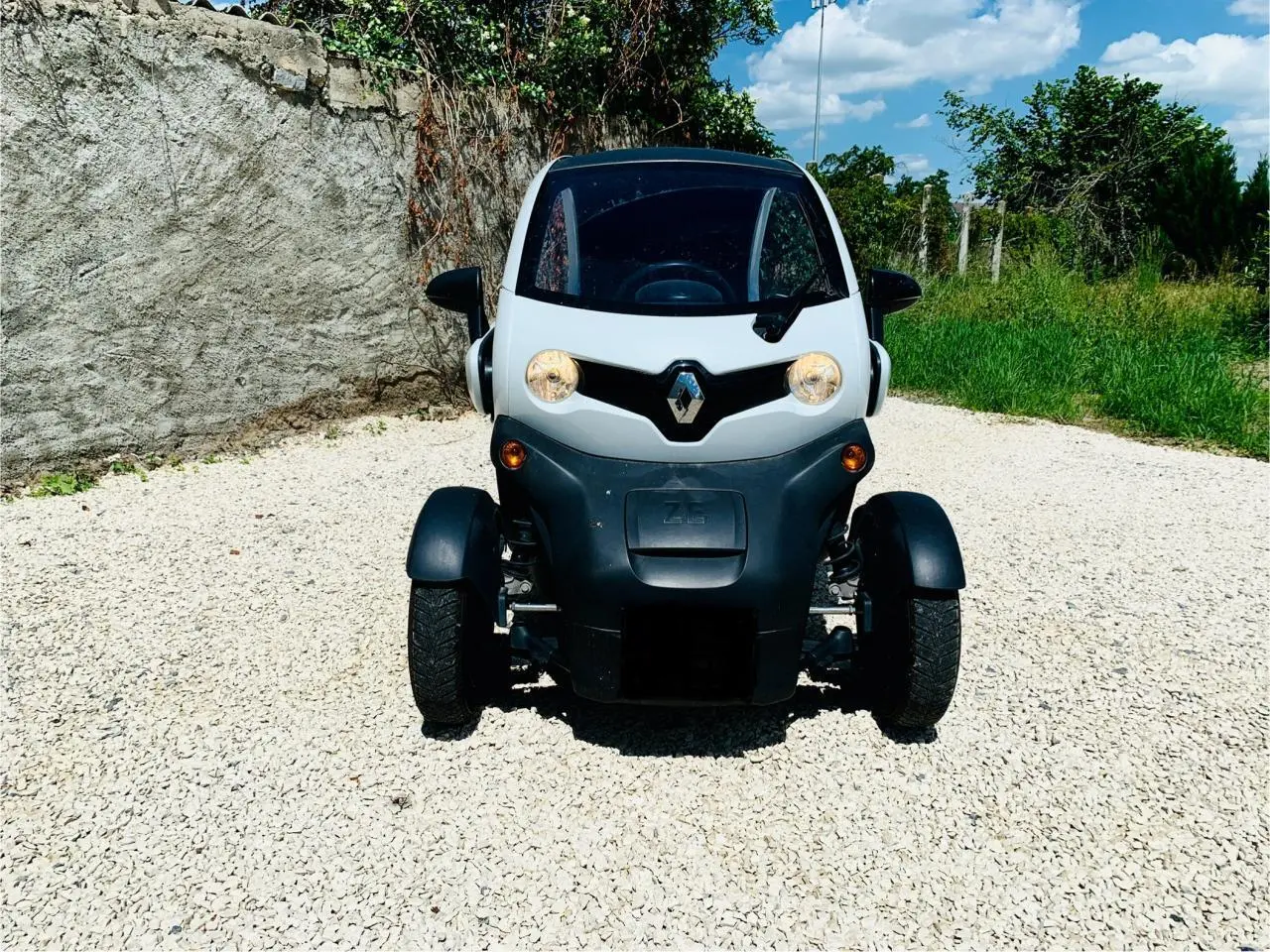 Vue frontale d'une Renault Twizy blanche électrique 2019, avec phares allumés et logo Renault bien visible.