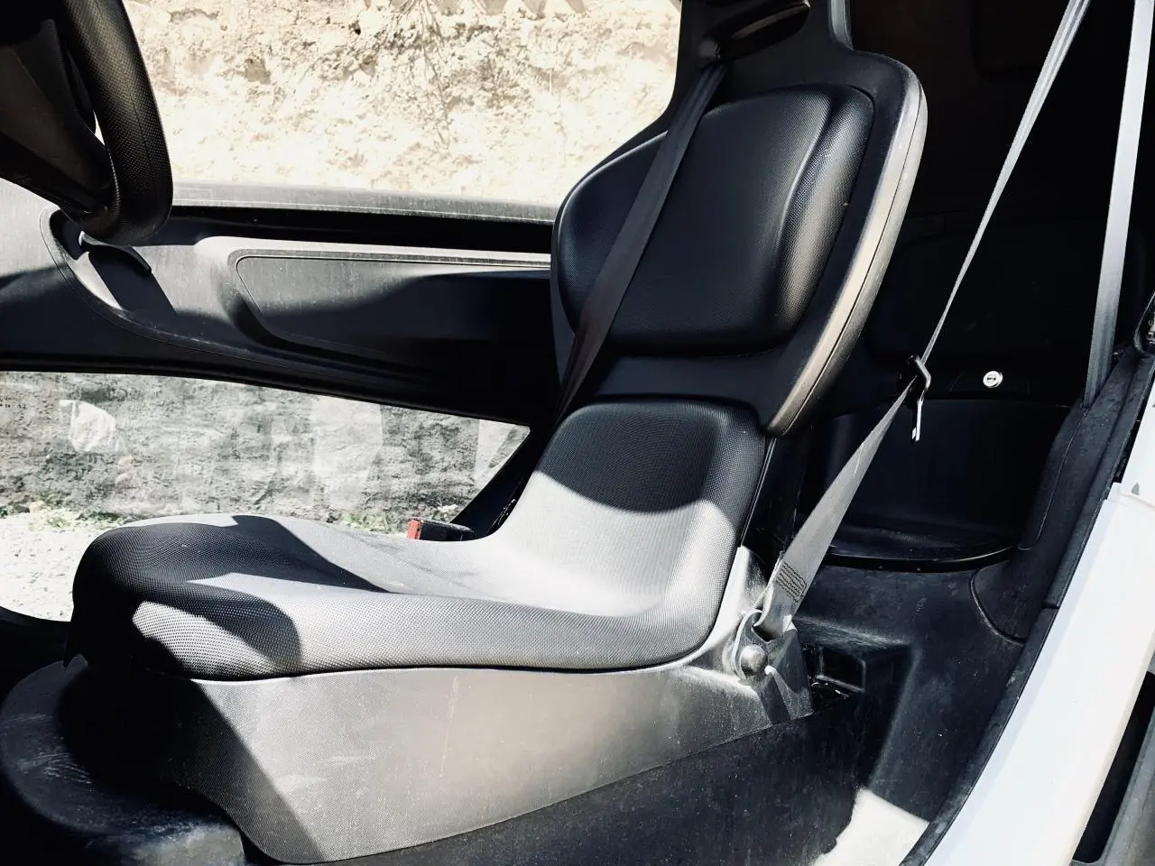 Vue intérieure côté droit du siège avant noir du Renault Twizy blanc avec ceinture de sécurité visible.