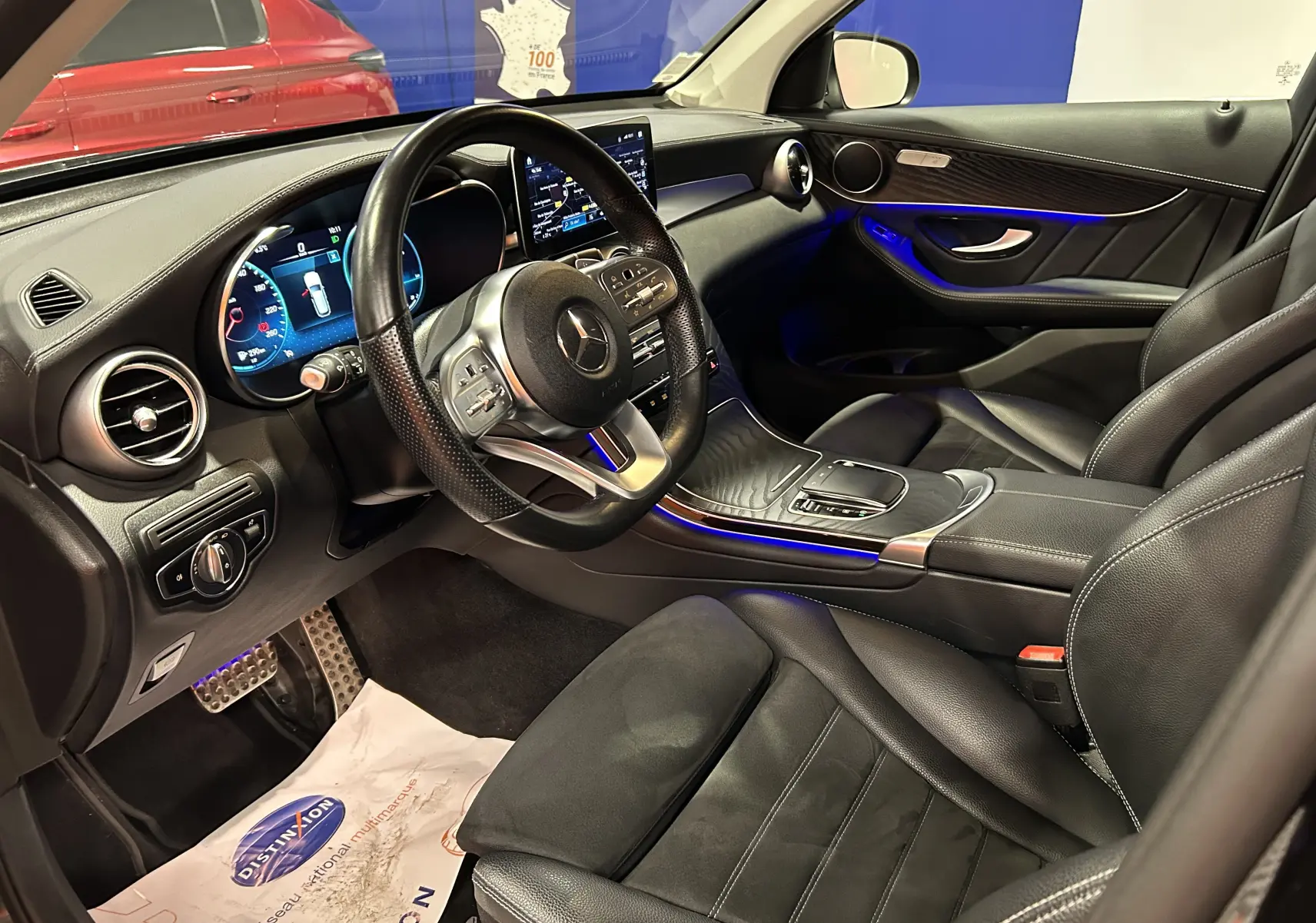 Intérieur noir cuir du Mercedes GLC 220D AMG Line vu côté conducteur, avec éclairage d'ambiance bleu et tableau de bord digital.