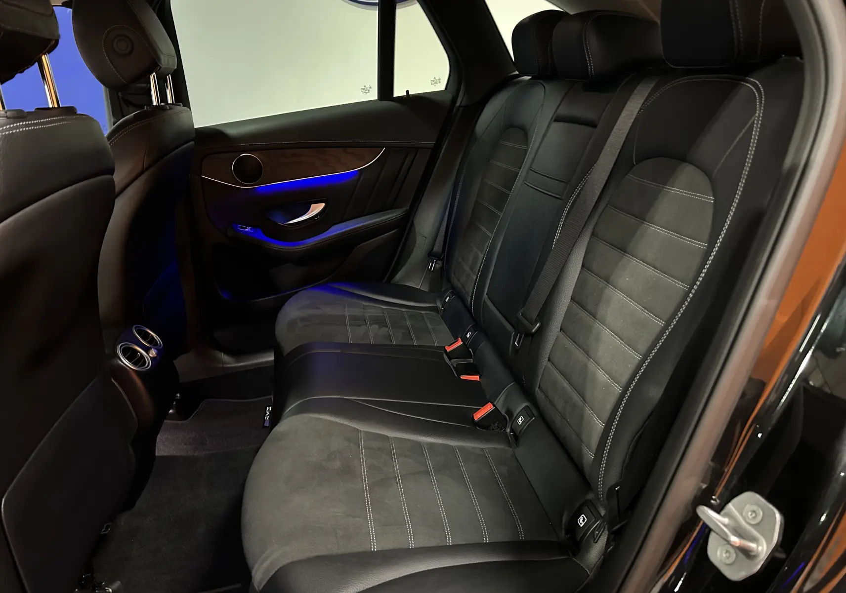 Vue intérieure arrière côté droit du Mercedes GLC 220D AMG Line 2021 avec sièges cuir et alcantara noirs et éclairage d'ambiance bleu.