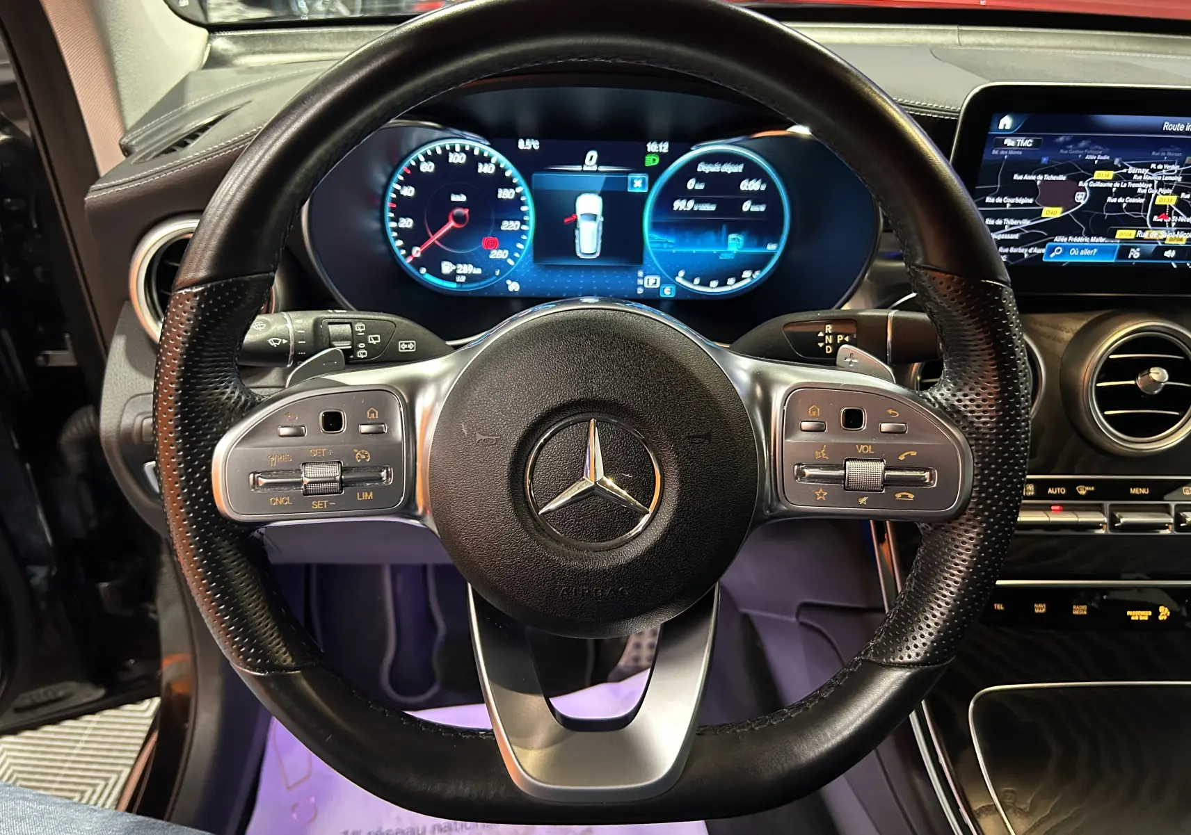 Vue rapprochée du volant cuir perforé noir et du tableau de bord numérique d'une Mercedes GLC 220D AMG Line 2021.