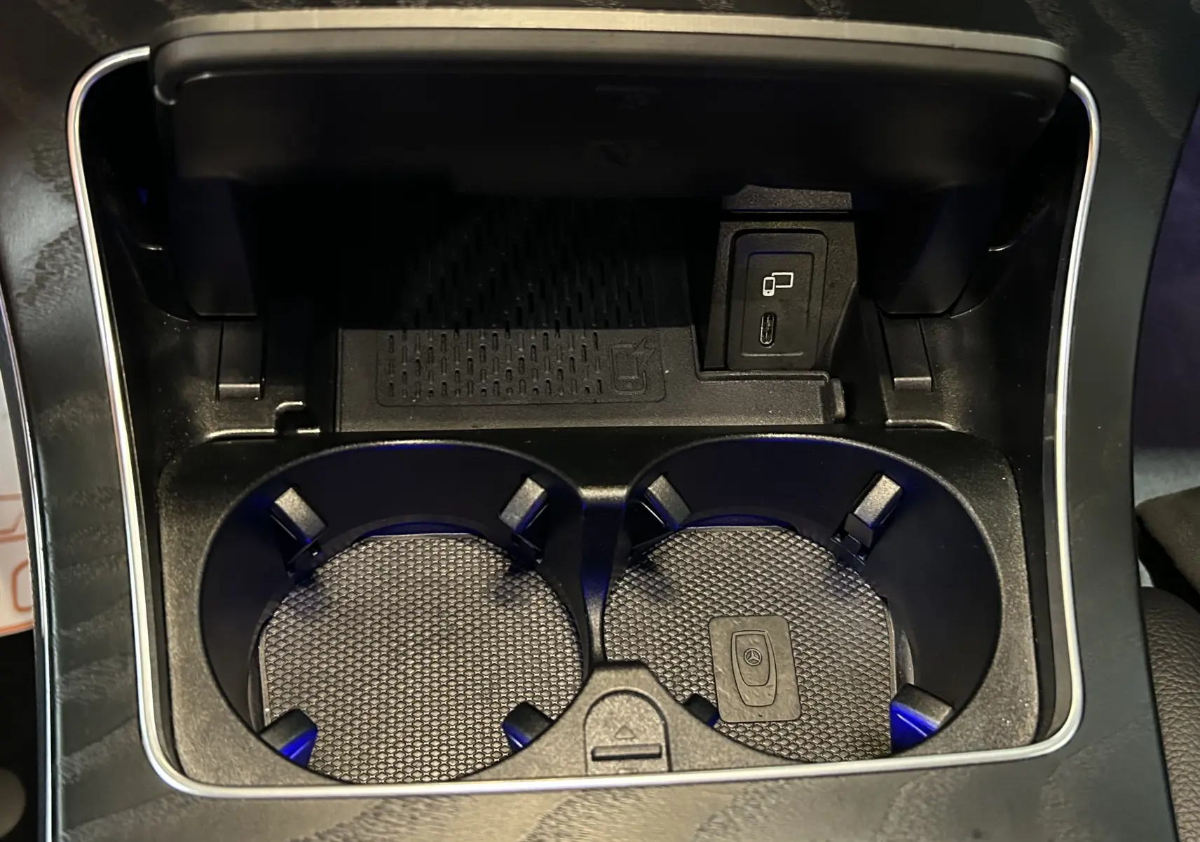 Gros plan sur les porte-gobelets et prise USB dans la console centrale d’un Mercedes GLC 220D AMG Line noir.