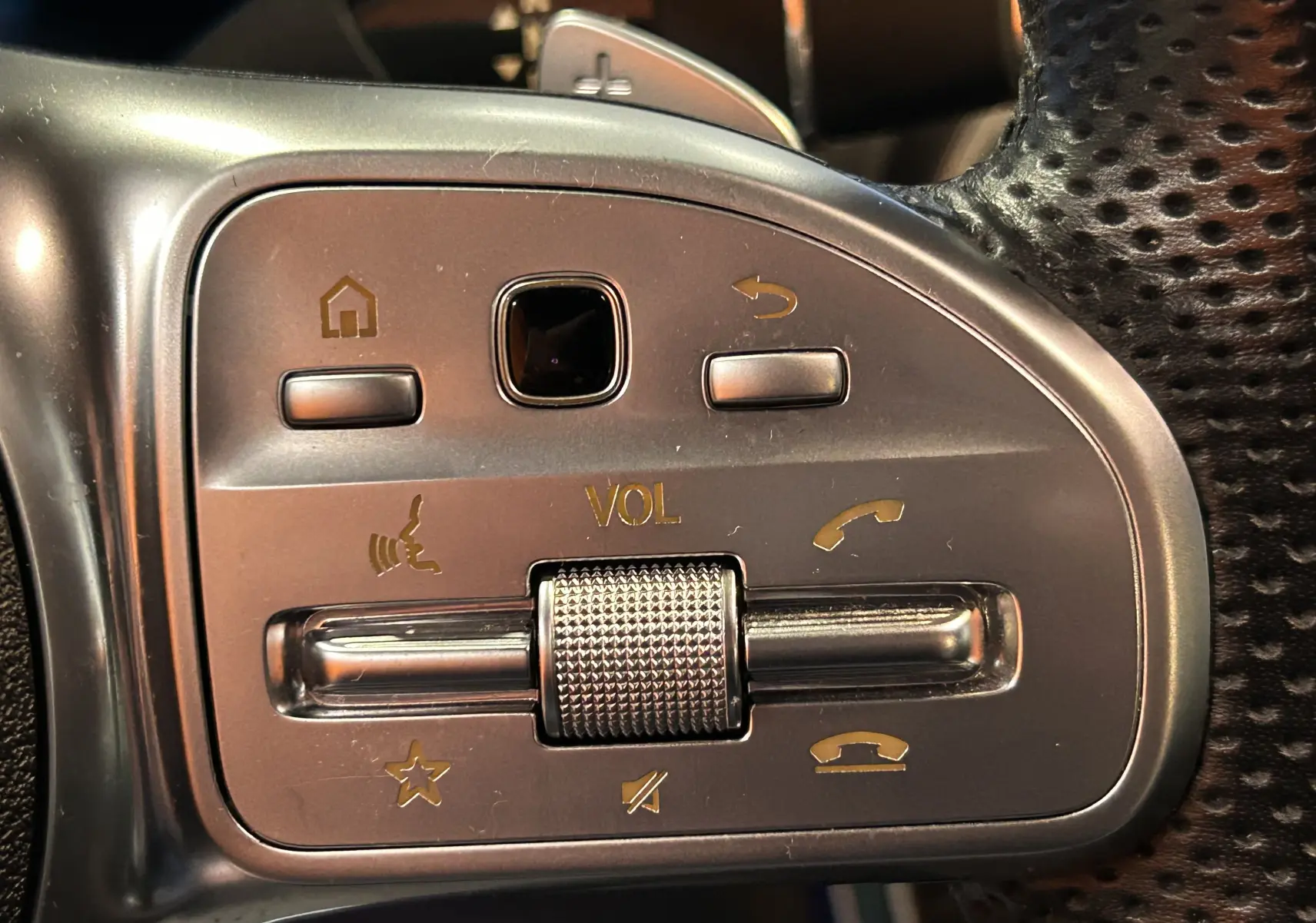 Gros plan sur les commandes de volume et appels au volant cuir perforé du Mercedes GLC 220D AMG Line noir Obsidienne.