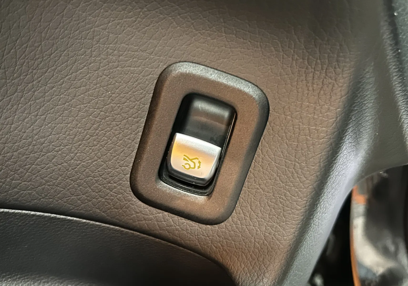 Gros plan sur le bouton d'ouverture électrique du hayon, entouré de cuir noir à l'intérieur du Mercedes GLC 220D AMG Line.