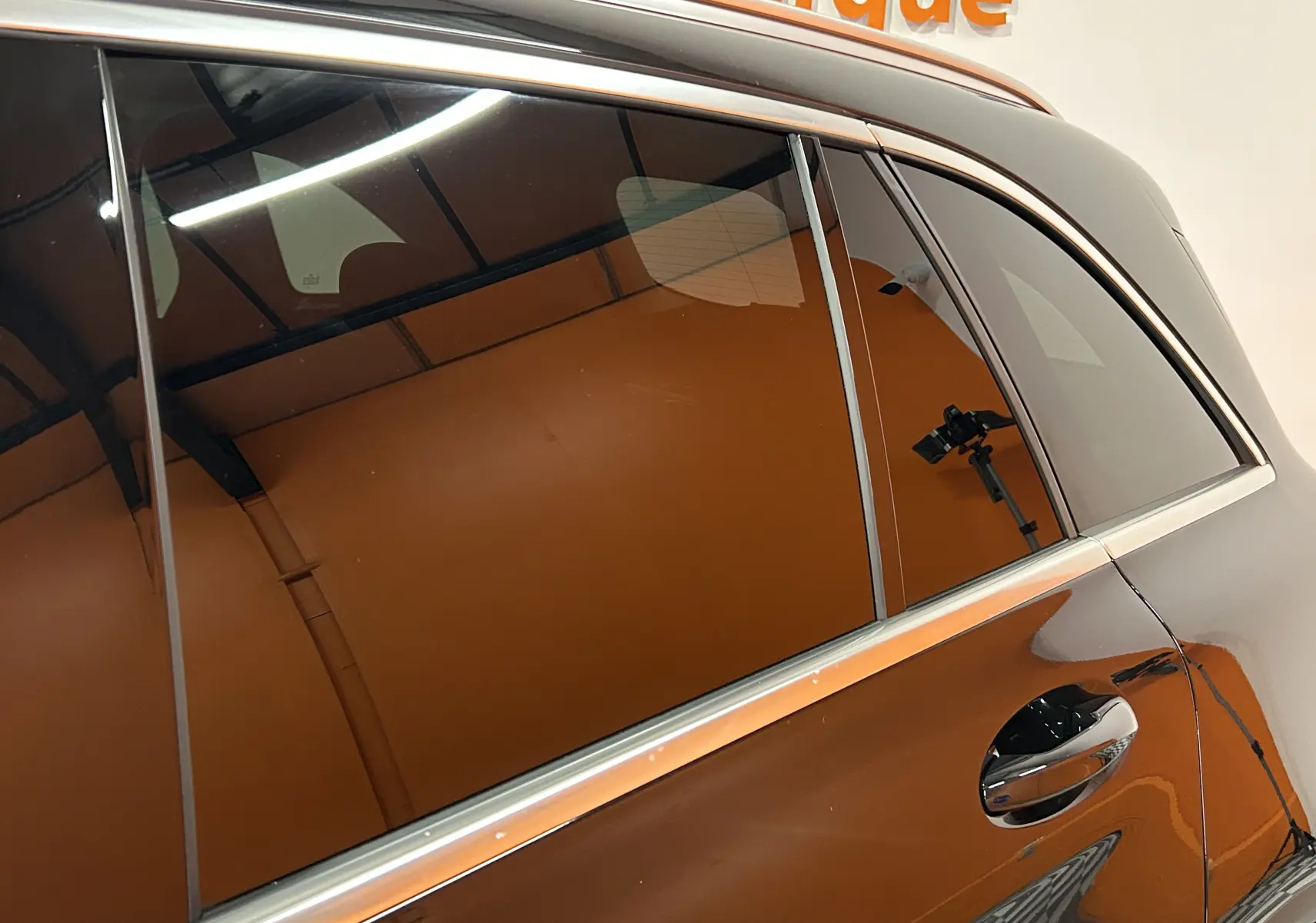 Vue rapprochée du côté gauche arrière du Mercedes GLC 220D AMG Line noir Obsidienne métallisé avec poignées chromées.