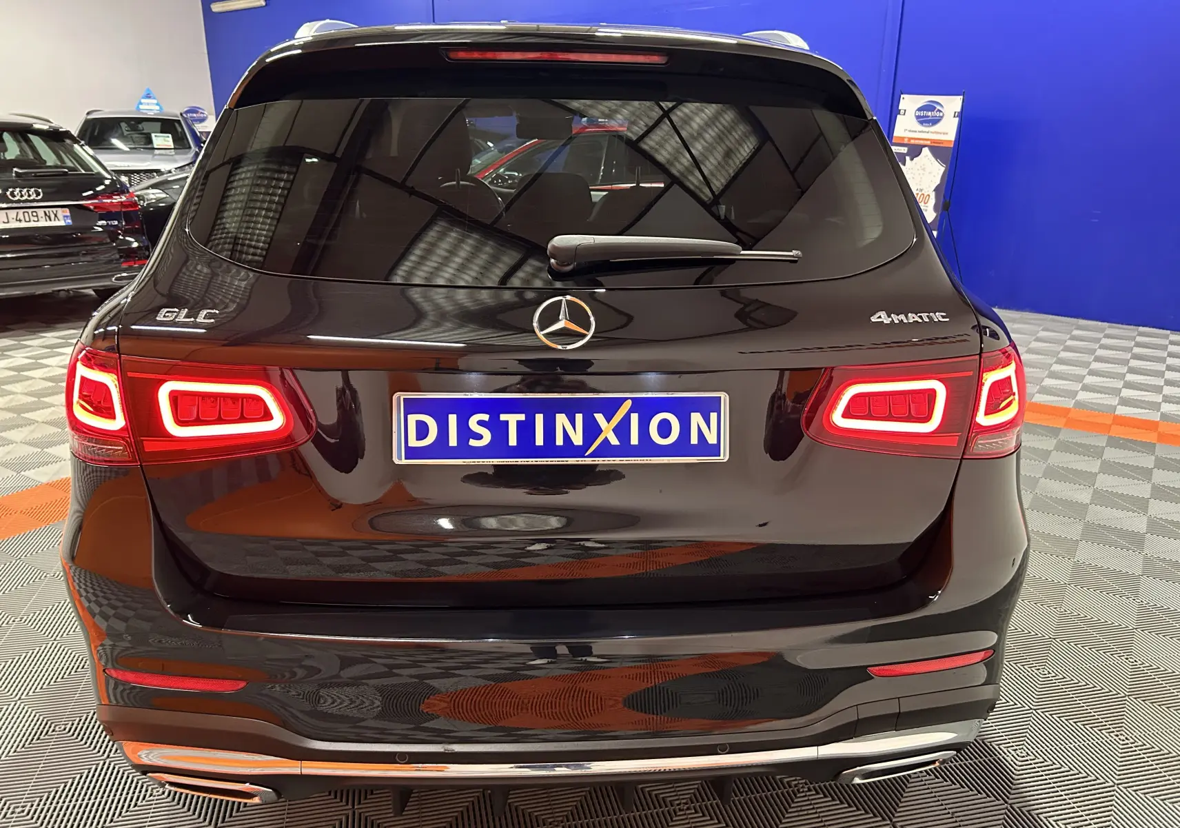 Vue arrière d’un Mercedes GLC 220D AMG Line noir Obsidienne métallisé avec feux LED allumés dans un showroom.