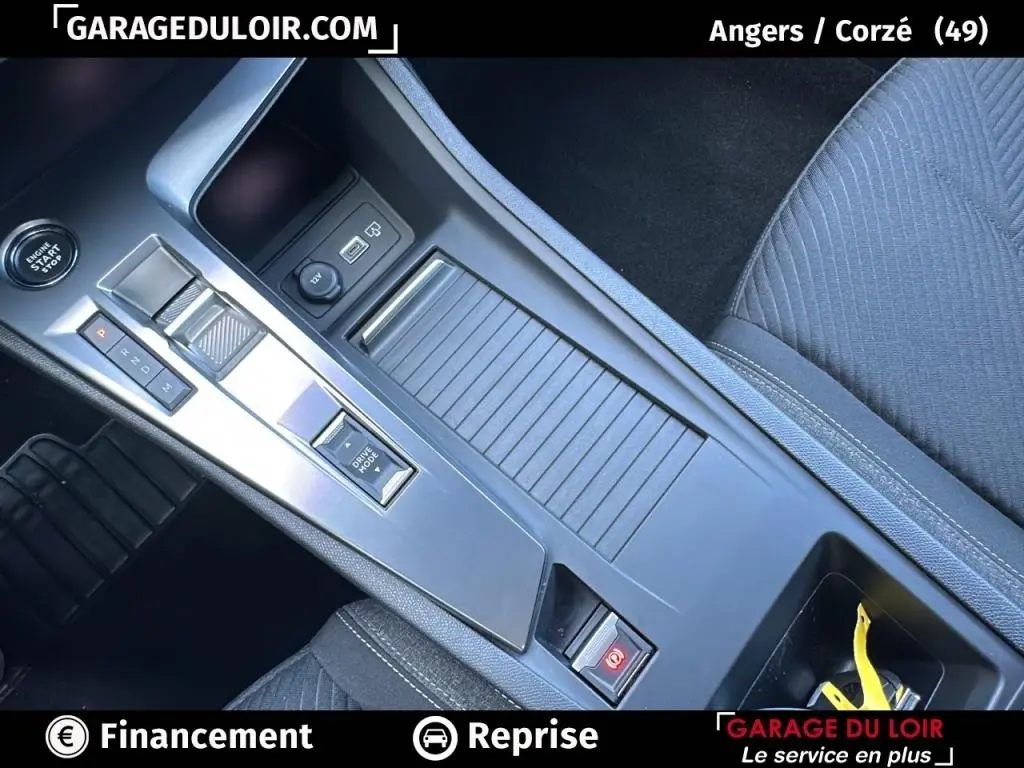 Vue rapprochée de la console centrale grise de la Peugeot 308 2023 avec boîte auto et bouton start/stop visible.