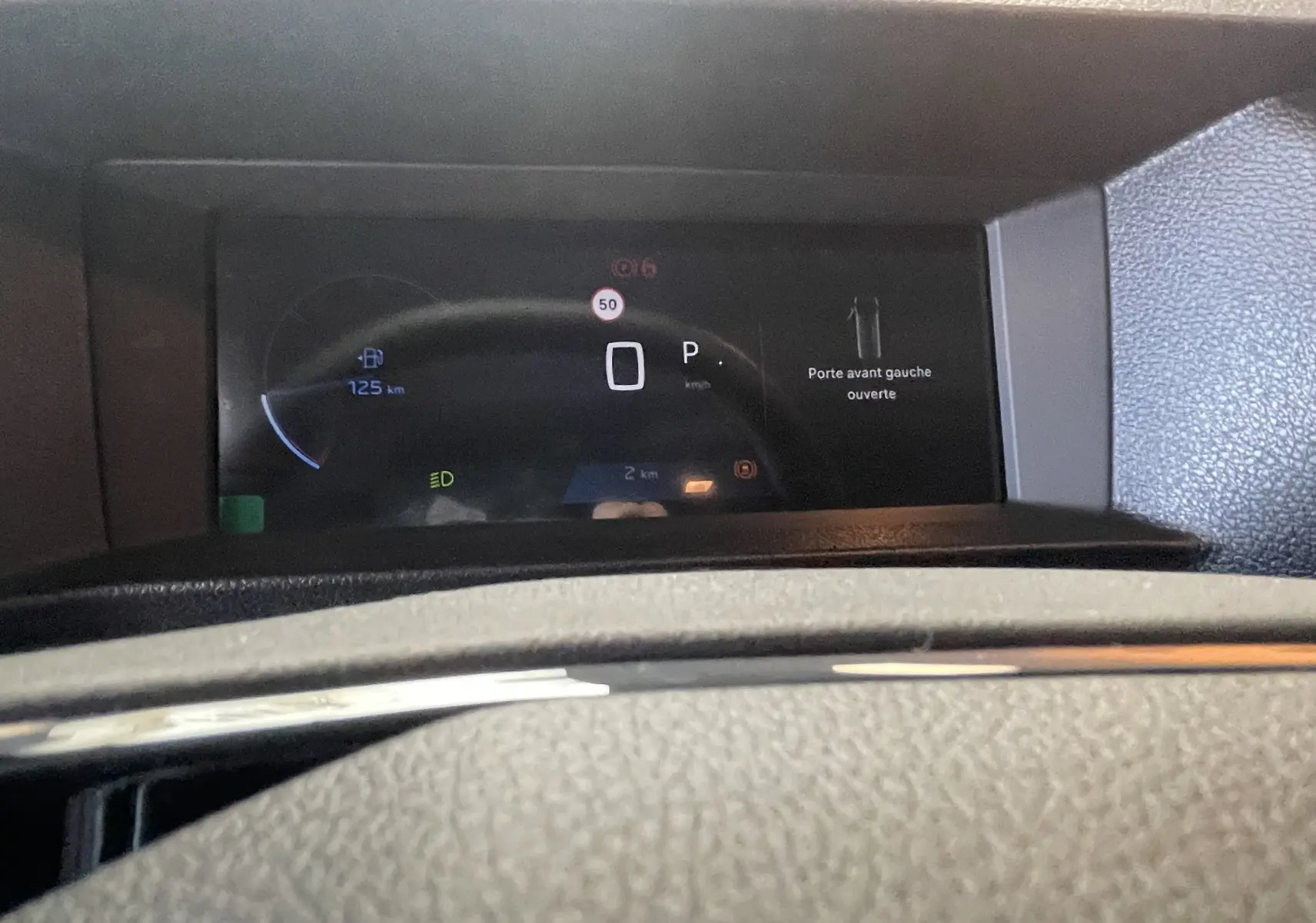 Vue du tableau de bord numérique du Peugeot Traveller 2026, affichant la porte avant gauche ouverte et l'autonomie restante.