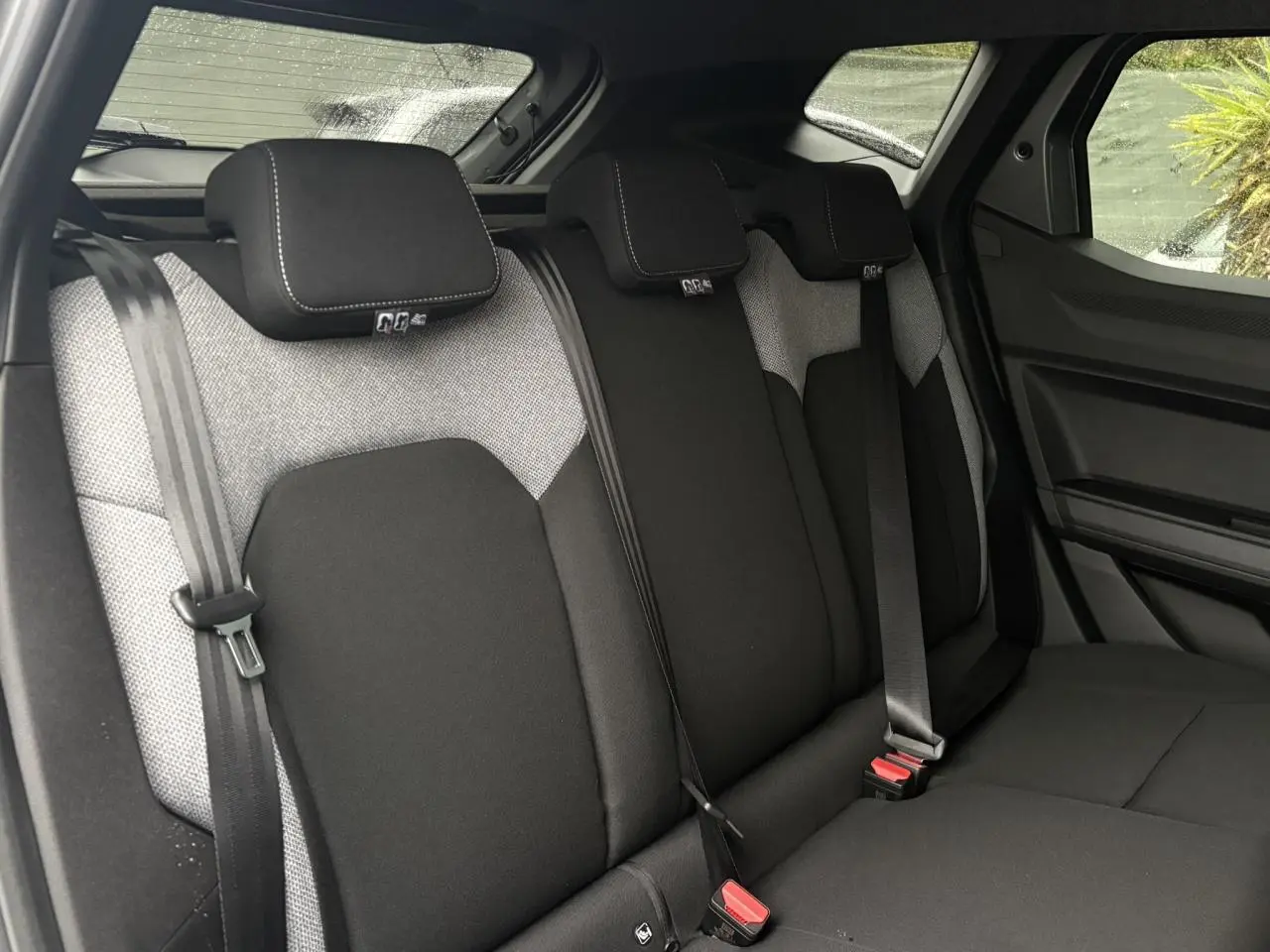 Vue intérieure des sièges arrière du Dacia Duster 2026, tissu noir et gris avec ceintures de sécurité visibles.