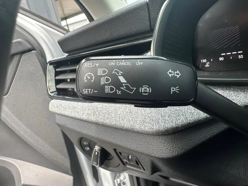 Gros plan sur la commande de régulateur de vitesse à gauche du volant dans l'habitacle gris argenté du Skoda Scala 2025.