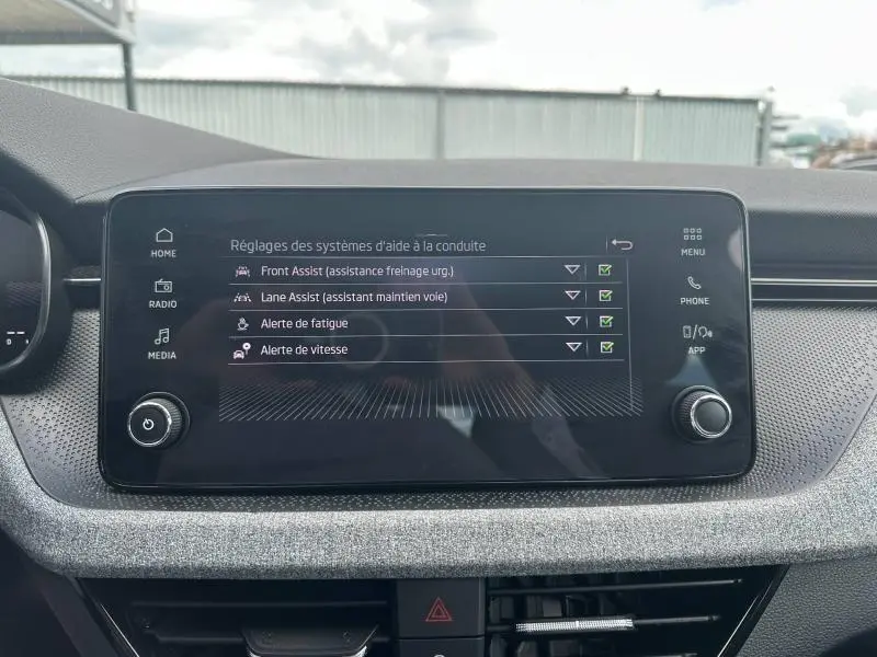 Écran tactile central de la Skoda Scala 2025 gris argent, affichant les réglages d'aides à la conduite.