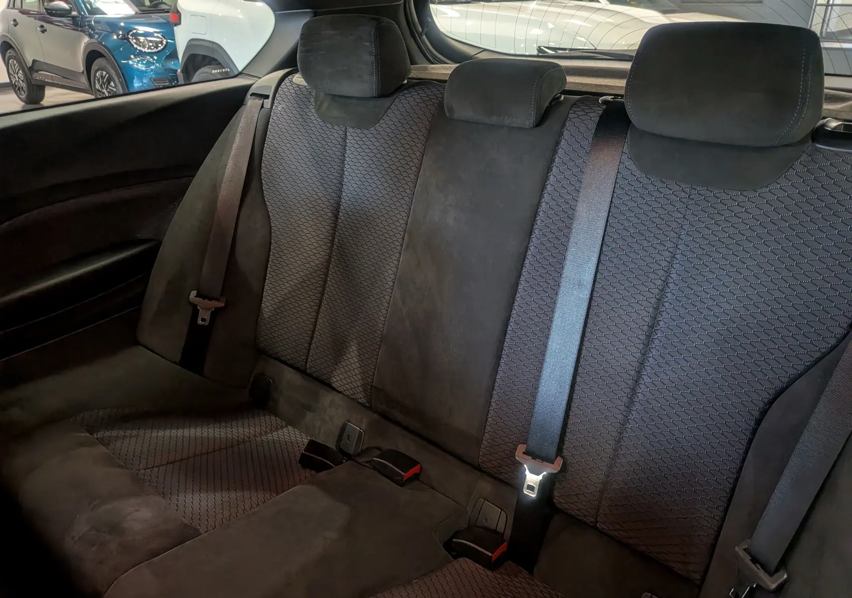 Vue intérieure montrant la banquette arrière en tissu et alcantara noir de la BMW Série 1 F21 118d M Sport.