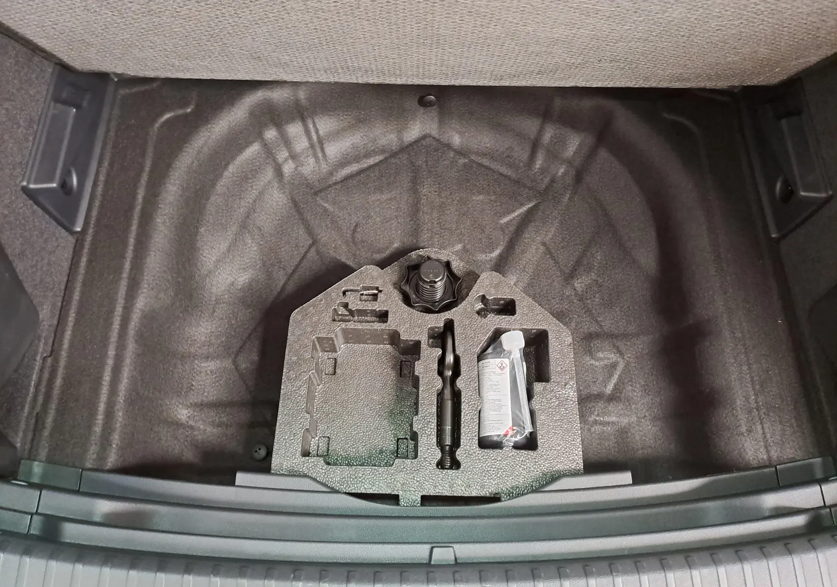 Vue plongeante sur le coffre ouvert du SEAT Ateca 2025, montrant le rangement sous plancher avec kit de réparation.