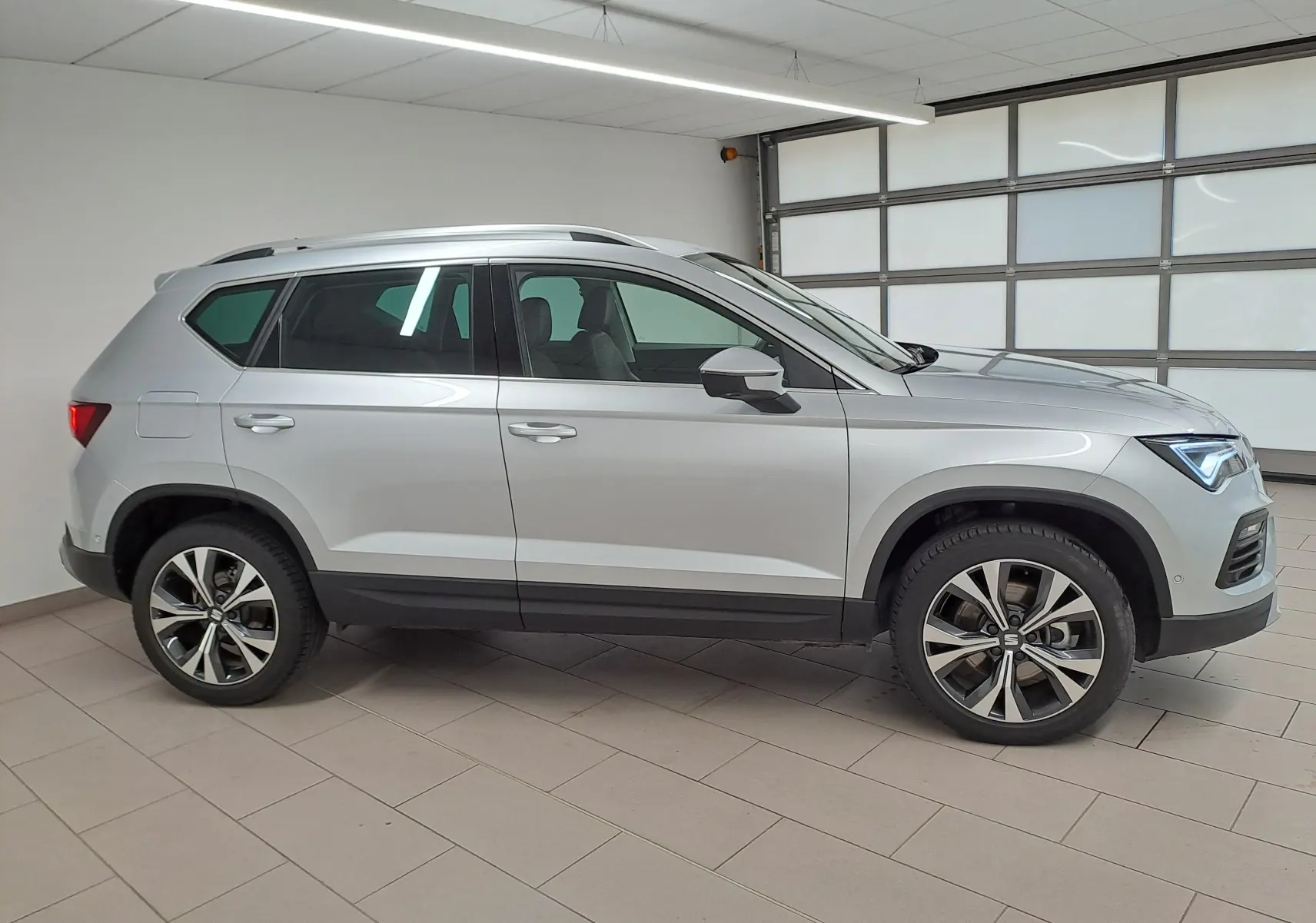 Vue de profil côté gauche d'un SEAT Ateca 2.0 TDI 150 DSG7 Copa argent métallisé avec jantes alliage 18 pouces.
