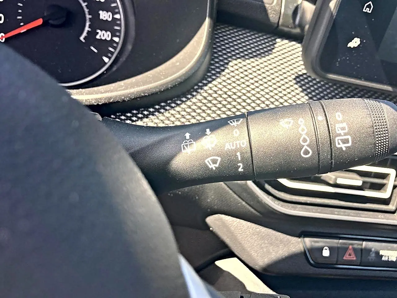 Gros plan sur la commande d’essuie-glace à gauche du volant dans l’habitacle noir de la Dacia Sandero 2025.