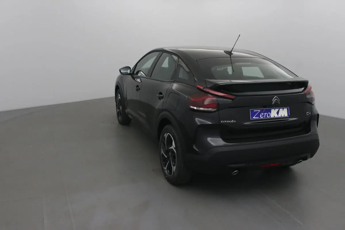 Vue 3/4 arrière droite d'une Citroën C4 noire 2022 avec toit plongeant et feux arrière distinctifs en forme de boomerang.