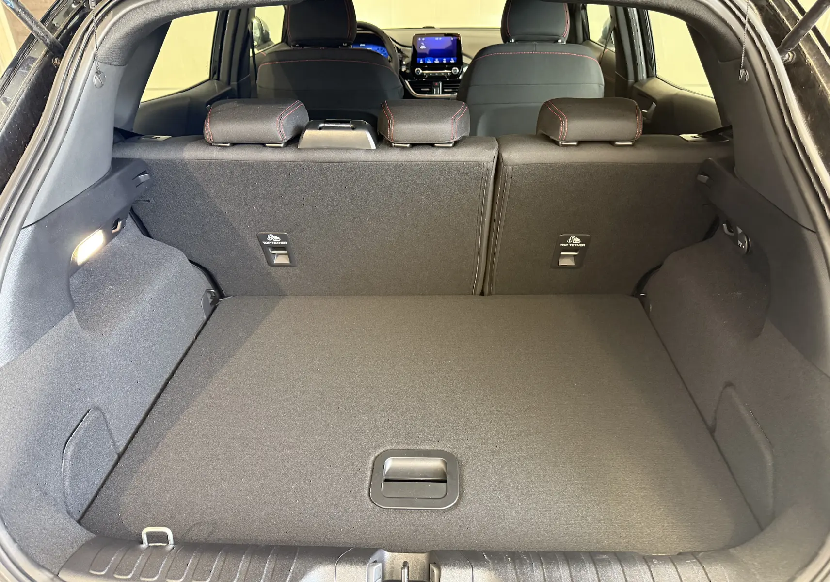 Coffre spacieux ouvert du Ford Puma noir Agate 2022, vue arrière avec sièges arrière et tableau de bord visibles.