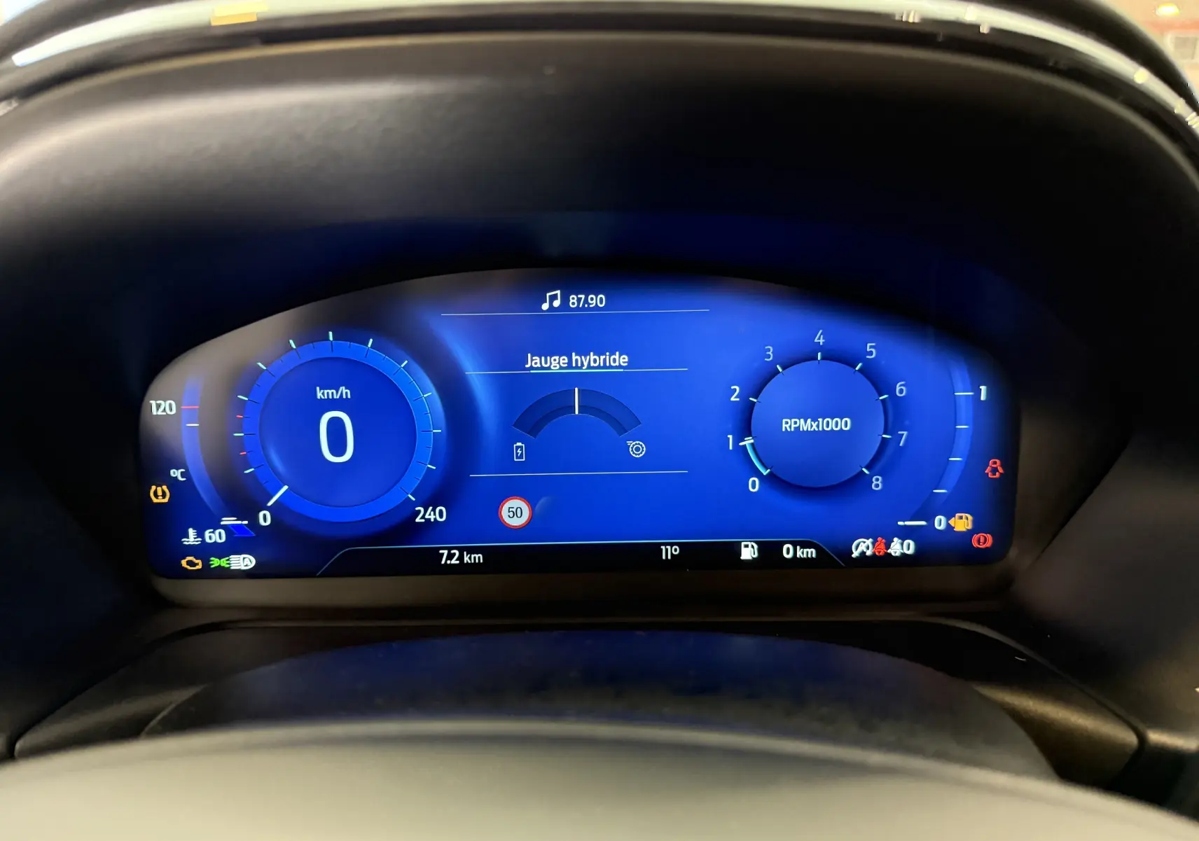Vue rapprochée du tableau de bord numérique bleu du Ford Puma 2022 affichant la vitesse, le régime moteur et la jauge hybride.