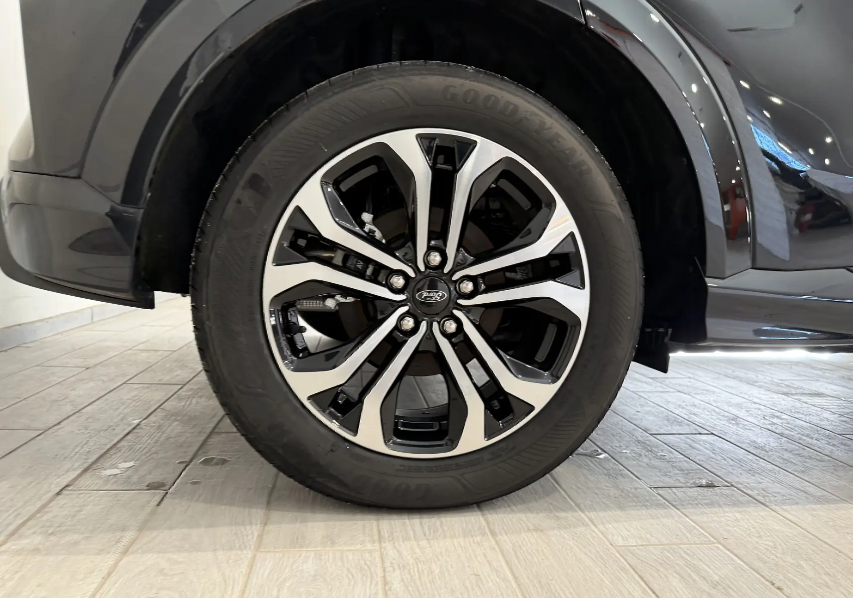 Gros plan sur la roue avant droite du Ford Puma noir Agate 2022 avec jante alliage bicolore et pneu Goodyear.