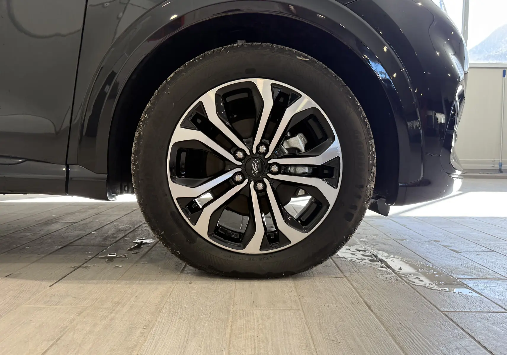 Gros plan sur la roue avant droite d’un Ford Puma noir Agate, mettant en valeur la jante alliage bicolore au design moderne.