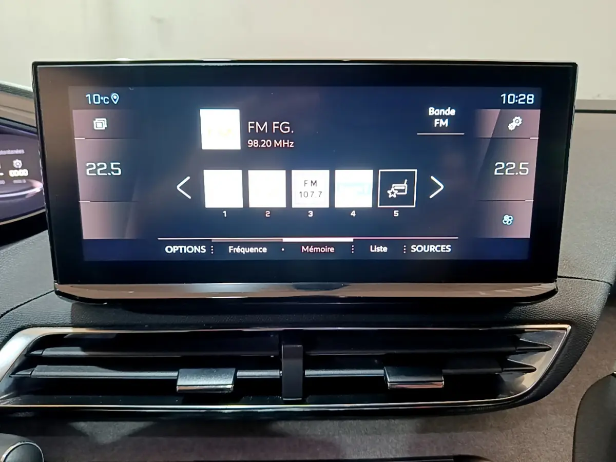 Écran tactile central du tableau de bord du Peugeot 3008 GT 2023 noir, affichant la radio FM et la température intérieure.