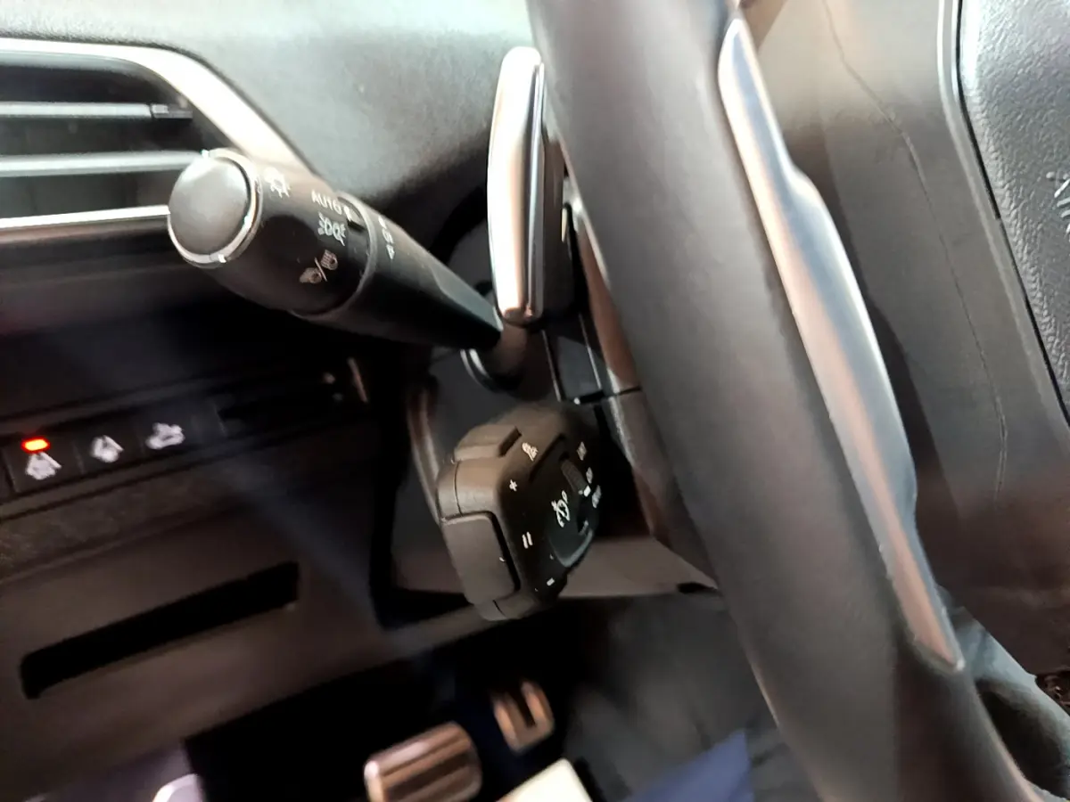 Gros plan sur la colonne de direction et commandes au volant du Peugeot 3008 noir 2023, intérieur moderne et épuré.