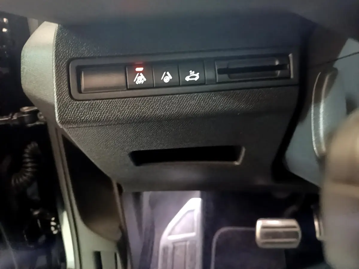 Gros plan sur les commandes sous le tableau de bord du Peugeot 3008 noir, avec pédale d'accélérateur visible à droite.