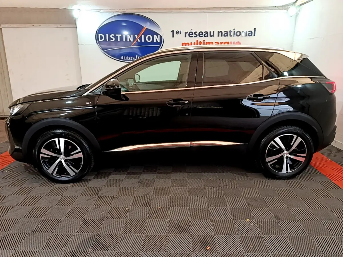 Profil côté gauche d'un Peugeot 3008 GT noir 2023, avec jantes alliage et vitres teintées en intérieur showroom.