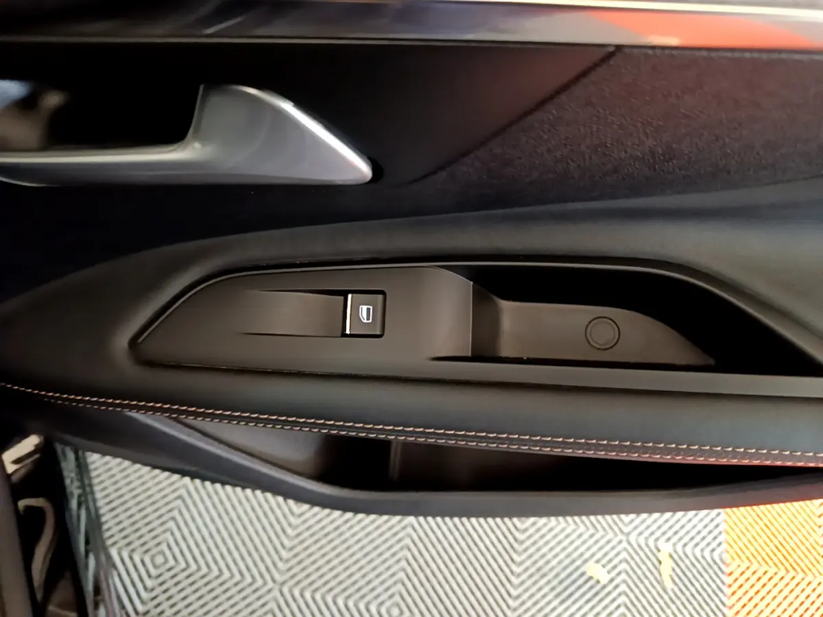 Gros plan sur la poignée intérieure et commande de lève-vitre côté gauche du Peugeot 3008 GT noir 2023.