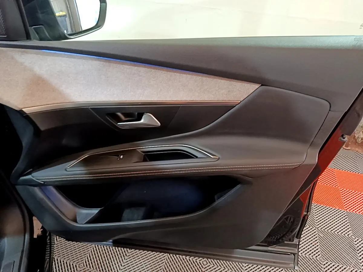 Vue intérieure côté gauche de la porte avant noire du Peugeot 3008 GT 2023 avec garniture tissu et coutures contrastées.