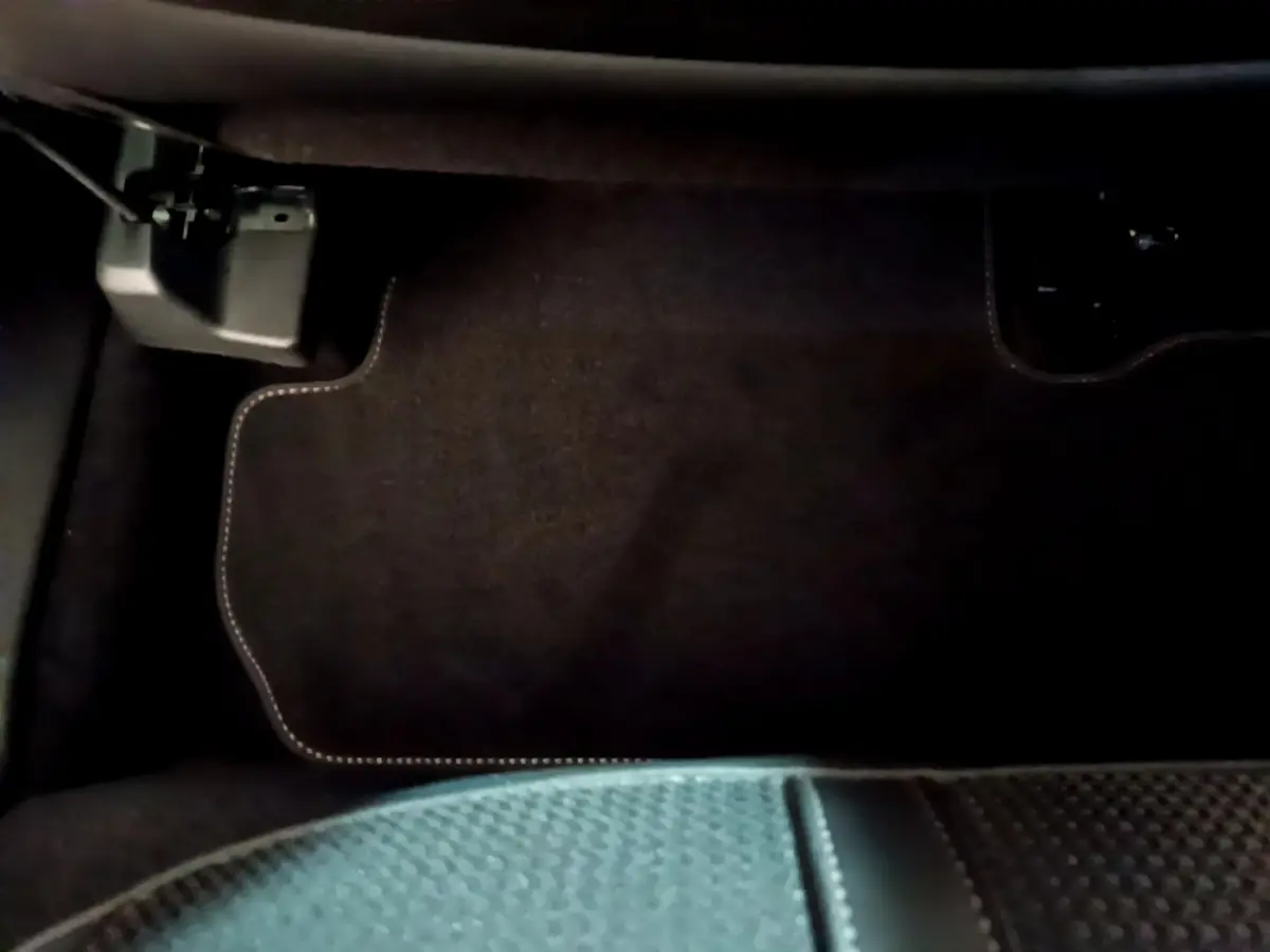 Gros plan sur le tapis de sol noir avec surpiqûres blanches côté conducteur du Peugeot 3008 GT 2023.